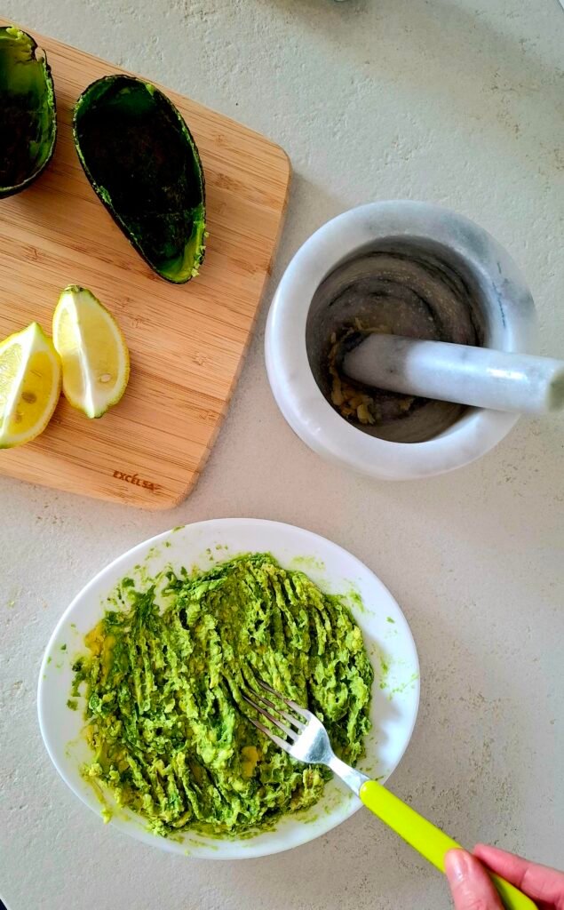 Preparazione guacamole con avocado schiacciato