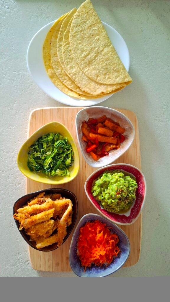 Ingredienti per tacos: tortillas, carote, zucchine, pollo, guacamole