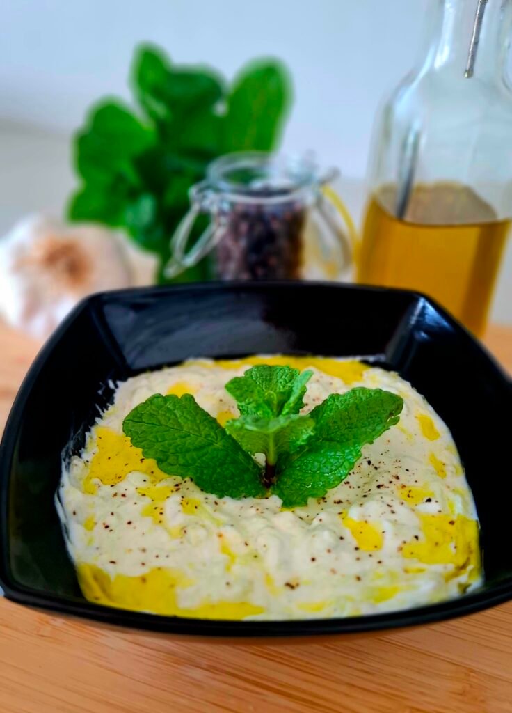 Salsa tzatziki densa e cremosa con olio e foglie menta pepe in ciotola nera che crea contrasto