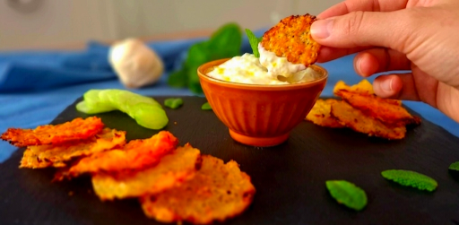 Mano che immerge la cialda croccante di patate nella salsa tzatziki 