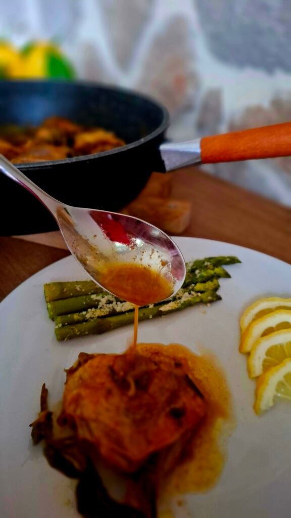 Cucchiaio che fa colare sughetto sulla faraona con contorno asparagi bolliti gratinati