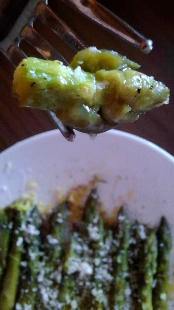 Zoom su punta asparago succulenta con sfondo di asparagi gratinati senza forno con parmigiano
