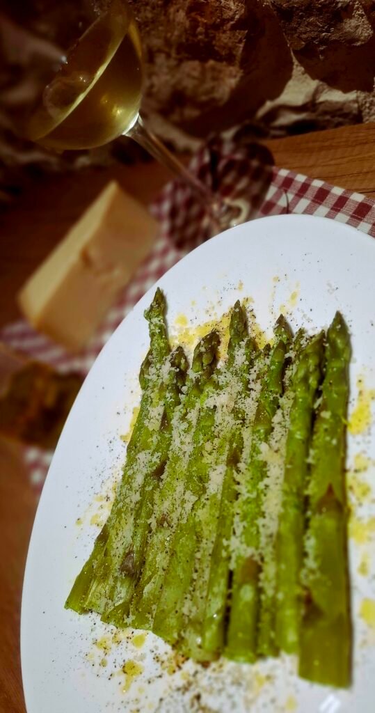 Atmosfera romantica con pietra a vista calice vino bianco piatto asparagi gratinato olio e parmigiano