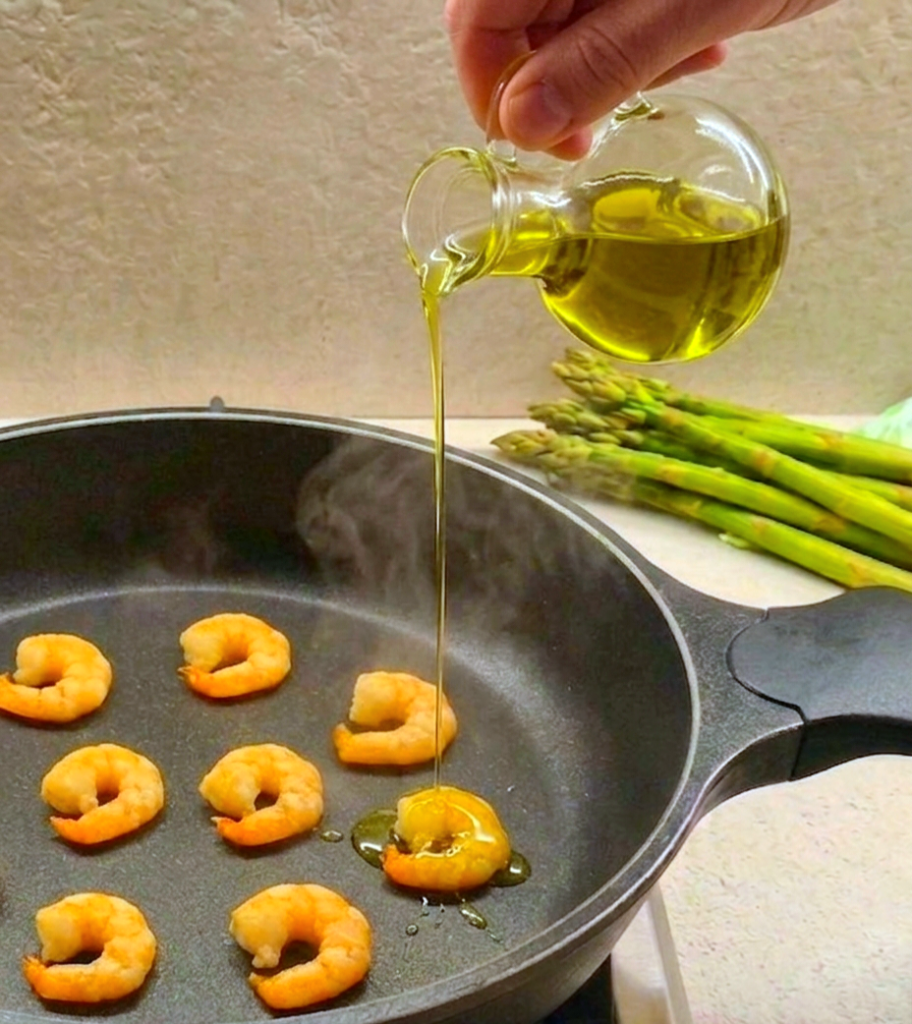 Olio versato a filo  su code mazzancolle da ampolla vetro con mano