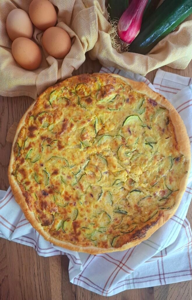 Quiche intera su tagliere con cestini con uova cipollotto e zucchine