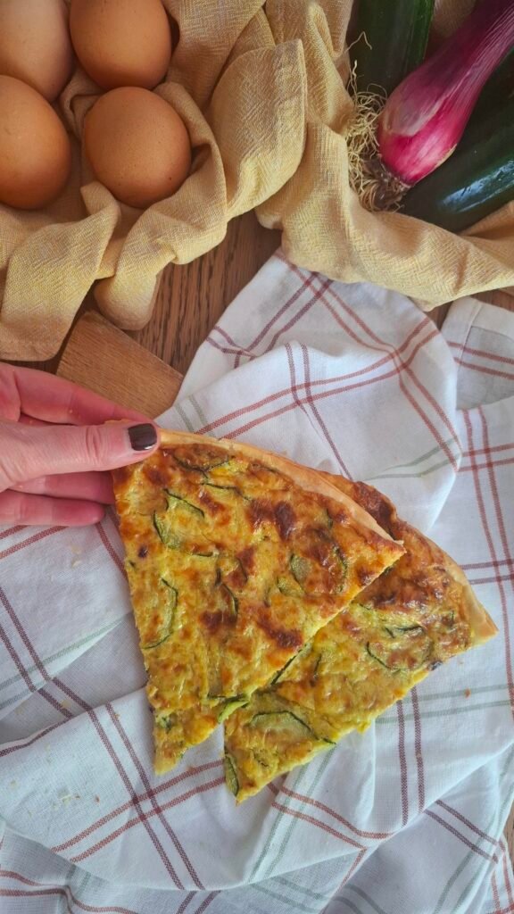 Mano che afferra torta salata zucchine crema di cipollotti