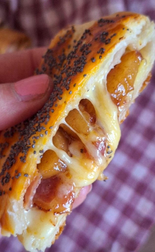 Cuore filante e succoso del fagottino aperto a metà dove fuoriescono scamorza, mele e speck