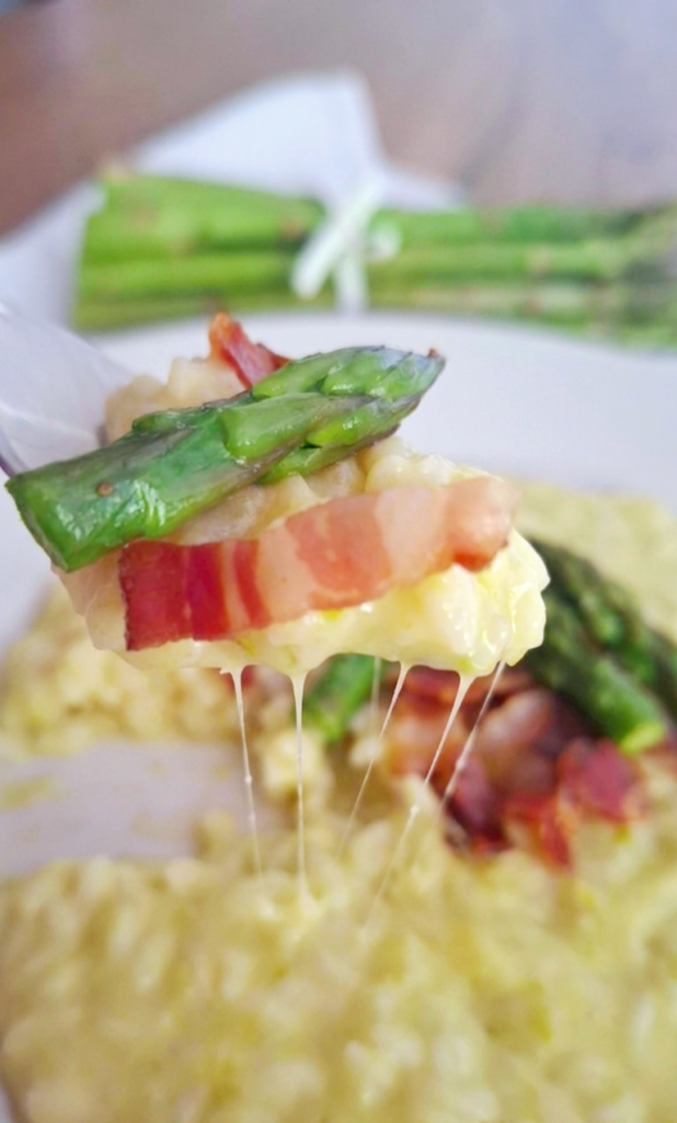 Forchetta che solleva risotto asparagi e pancetta con filamenti cremosi della mantecatura 