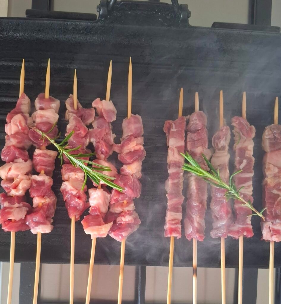 Griglia fumante con spiedini maiale e arrosticini pecora