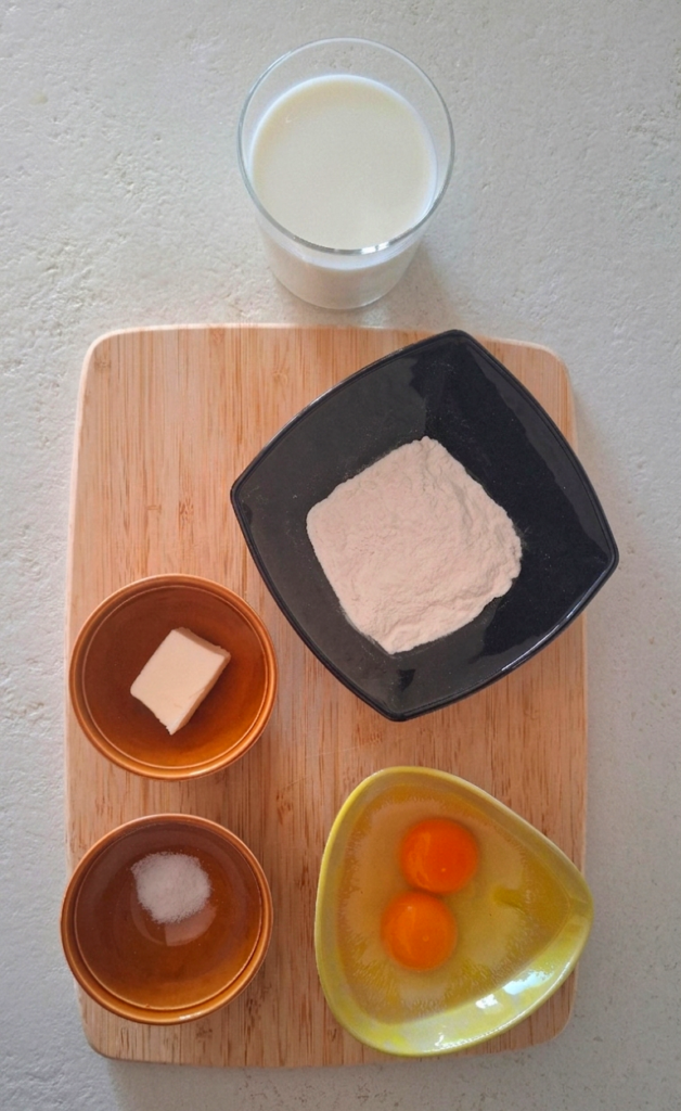 Ingredienti crepes su tagliere: uova, latte, farina, burro, sale