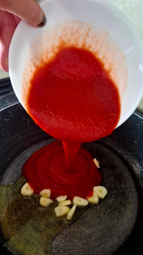 Salsa pomodoro versata in padella con olio e aglio