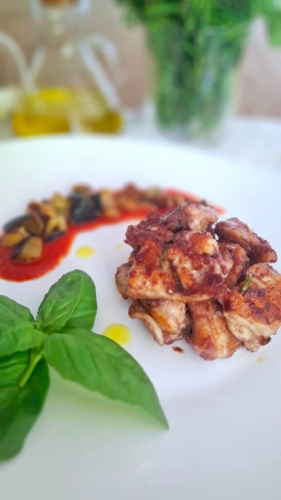 Bocconcini vino rosso croccanti disposti a cerchio con mezzaluna di melanzane a funghetto e fiore di basilico