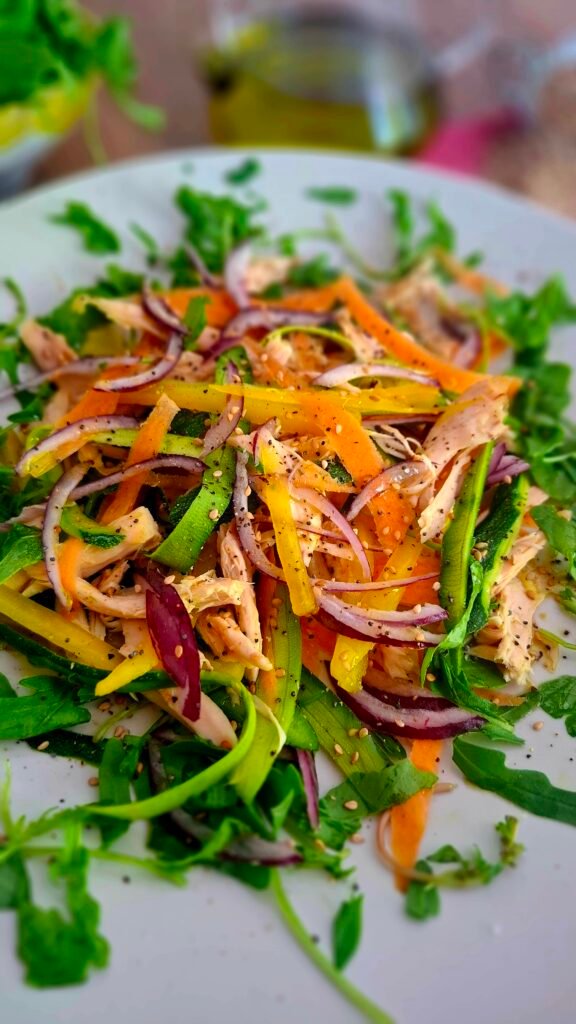 Primo piano su verdure e pollo cosparse di pioggia di semi di sesamo e papavero pepe olio e sale su piatto chiaro