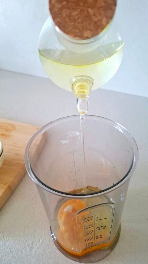 Olio di girasole e di arachidi versato a filo in bicchiere minipimer