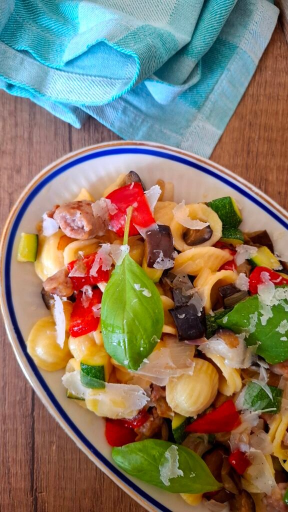 Piatto ovale con orecchiette con verdure saltate croccanti salsiccia basilico e lamelle parmigiano