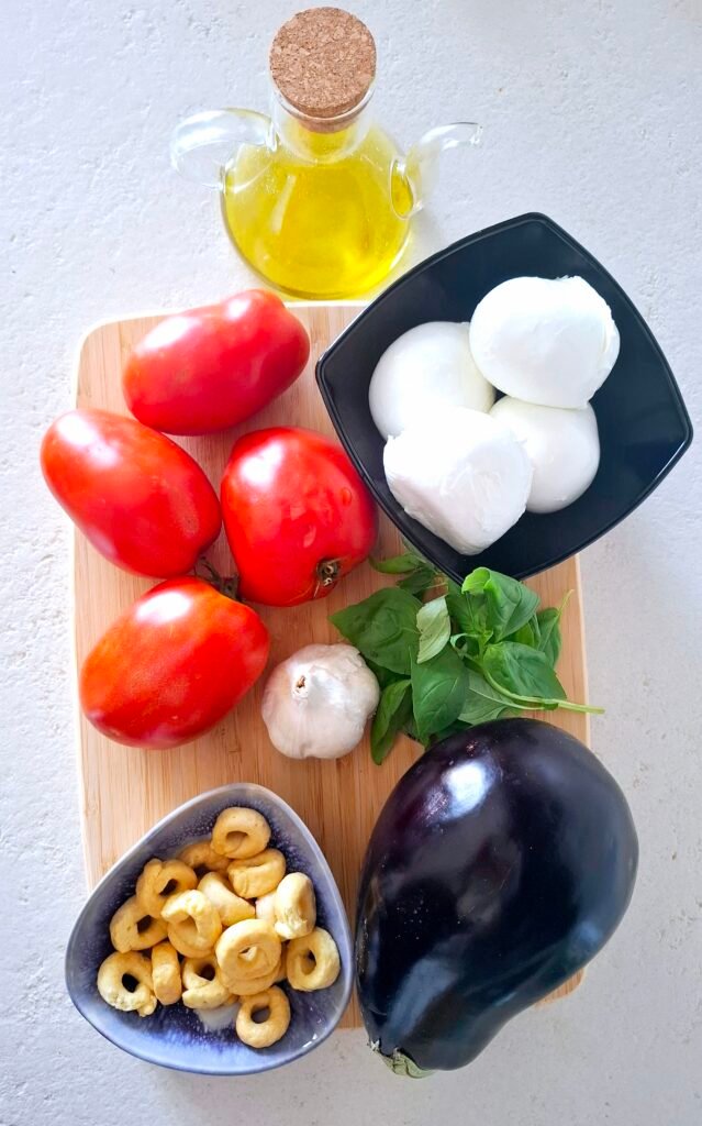 pomodori, mozzarella di bufala, aglio, olio extravergine d'oliva, melanzana, basilico e taralli su tagliere