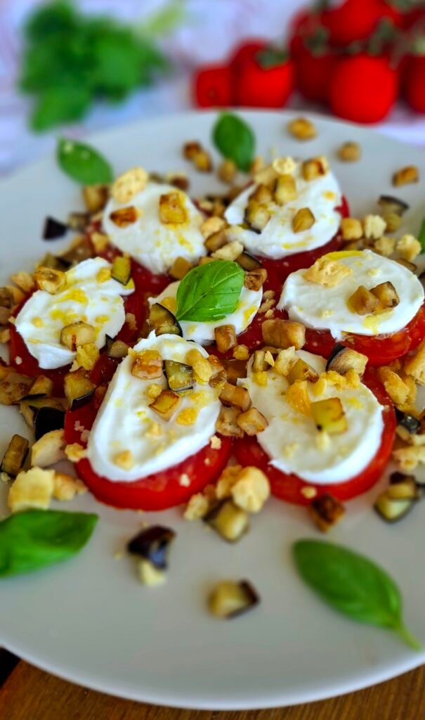 Parmigiana stile caprese: Zoom su cubetti melanzane mozzarella pomodori taralli sbriciolati e basilico