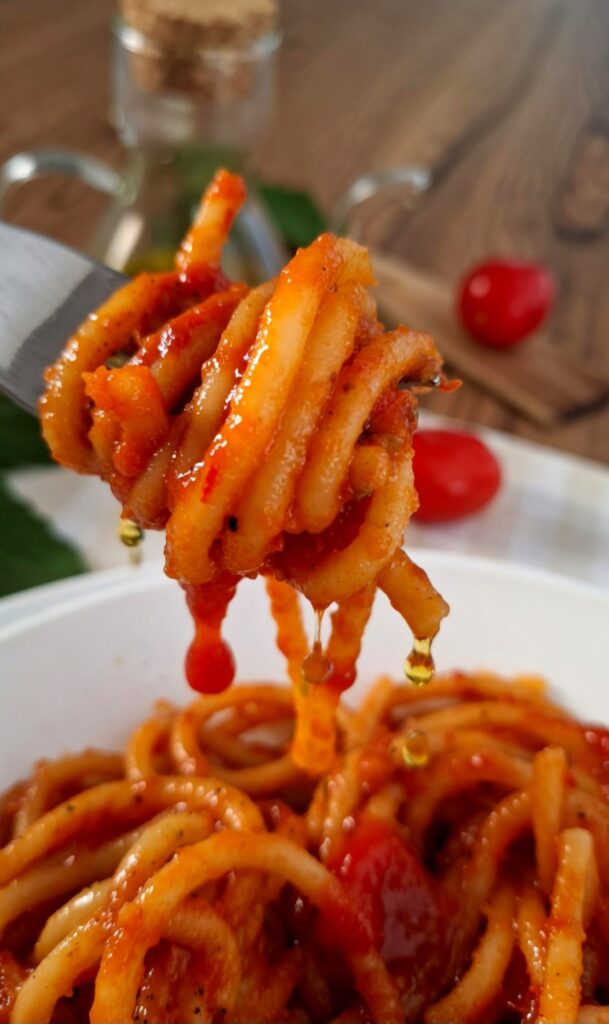 Boccone di pici aglione sulla forchetta molto succoso con sugo e olio che colano