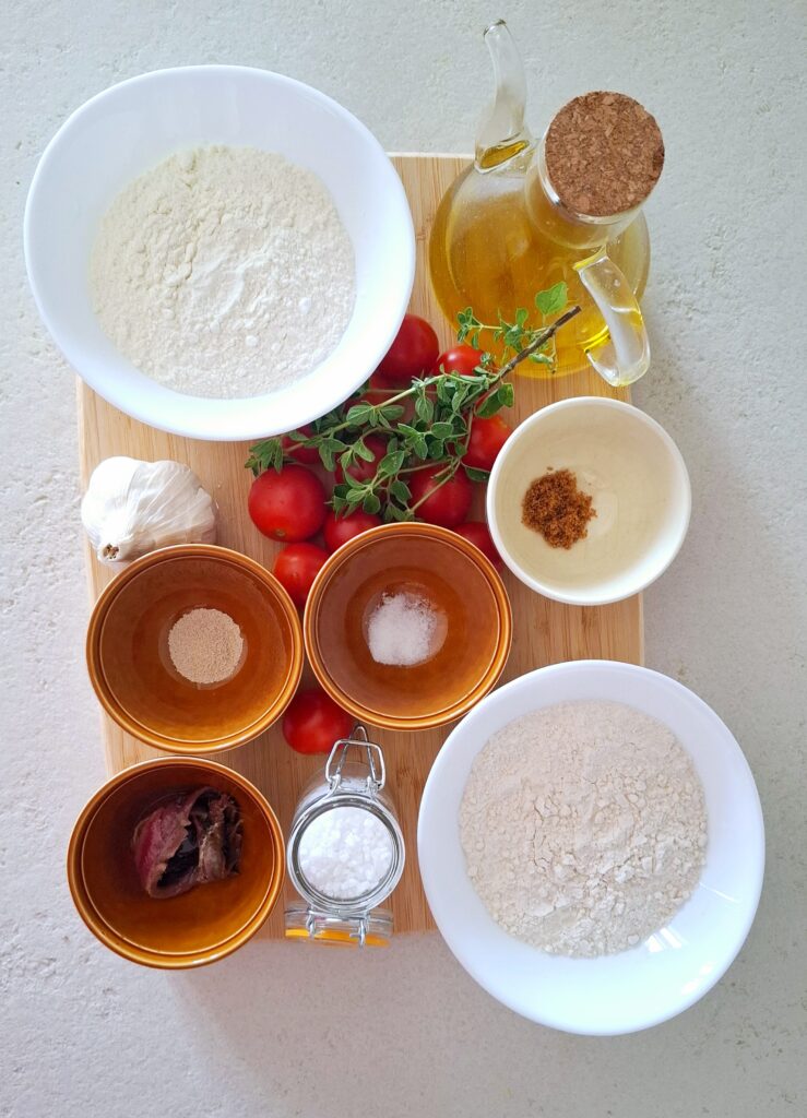 Ingredienti focaccia mediterranea sul tagliere:
farina Manitoba, farina 00, acqua, lievito di birra secco, zucchero (io ho usato quello integrale), olio extravergine d'oliva, sale grosso, sale fino, pomodorini ciliegino, alici sott'olio, aglio, origano fresco.
