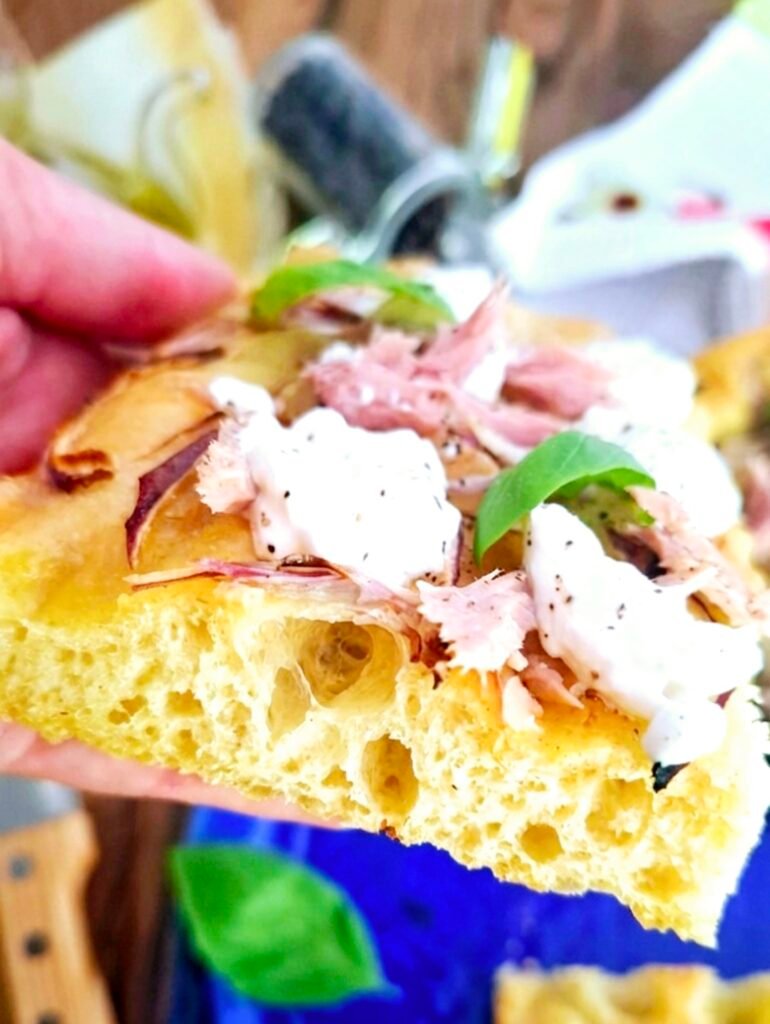 Alveoli evidenti in fetta di focaccia gourmet con tonno Cipolle basilico e burrata
