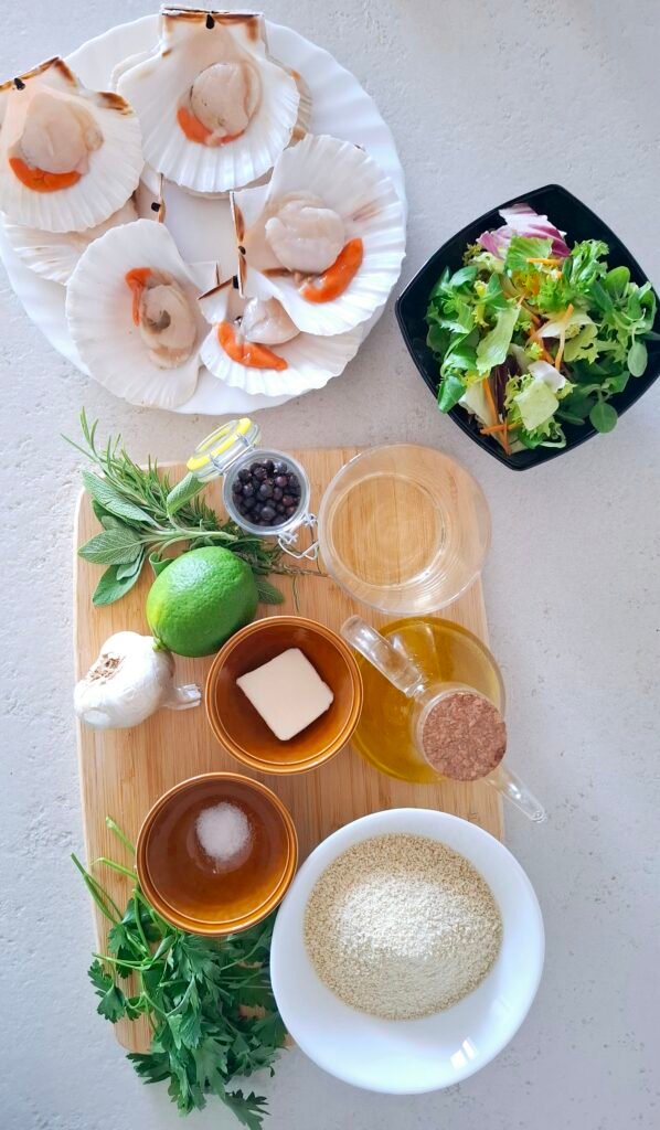Ingredienti su tagliere: le capesante, il pane grattugiato, l'aglio, il prezzemolo, il sale fino, pepe nero, burro, olio evo e infine l'insalatina misticanza e il lime come elementi facoltativi.
il vino bianco, l'olio extravergine d'oliva, l'aglio, la salvia e il rosmarino.