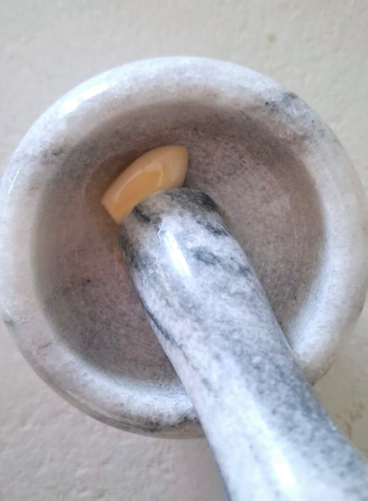 Aglio nel mortaio con goccio olio evo