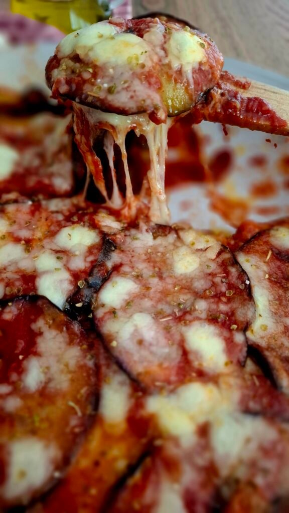 Spatola in legno che sollevato parmigiana di melanzane filante...non fritta ,non in forno ,con Mozzarella origano scamorza 