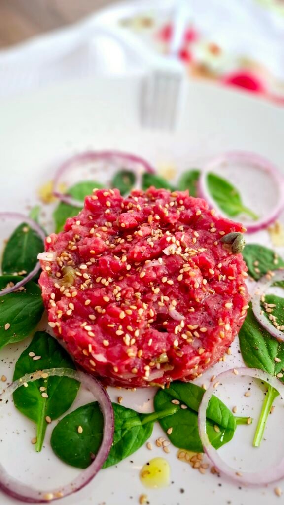 Tartare di manzo senza uovo con guarnizione di insalatina e cipollotti, croccante con semi di sesamo e condimento leggero