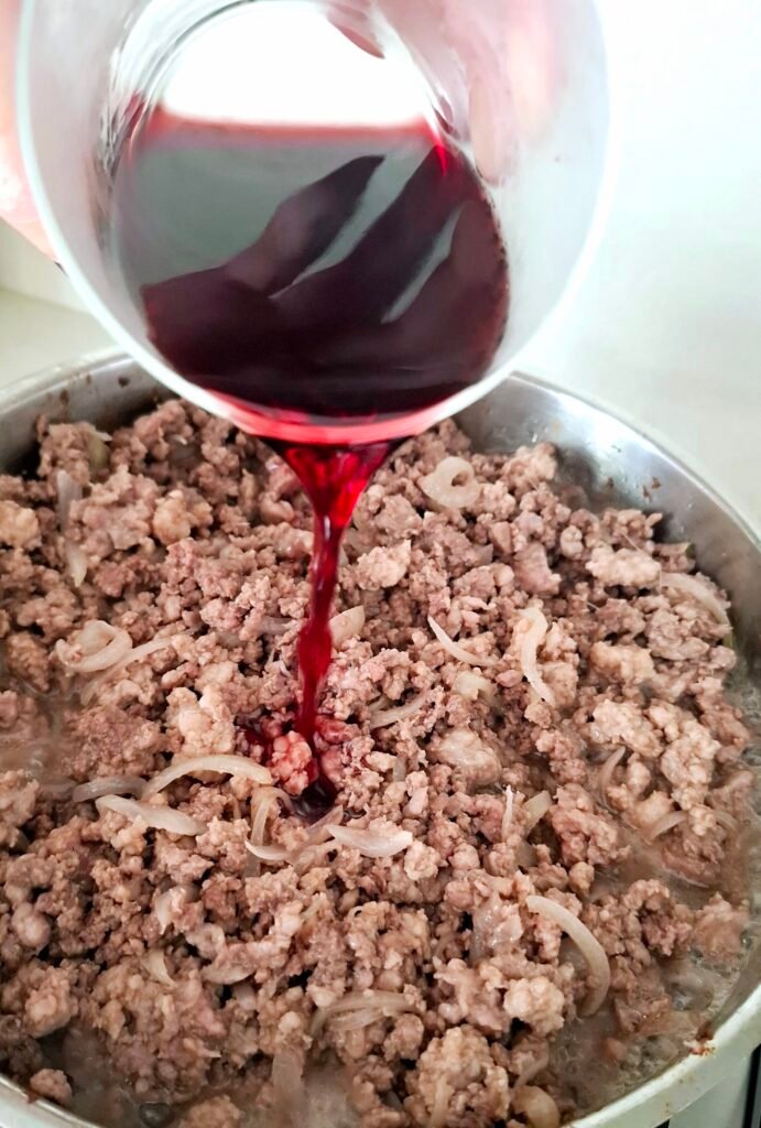 Aggiunta di vino rosso al ragù che va sfumato