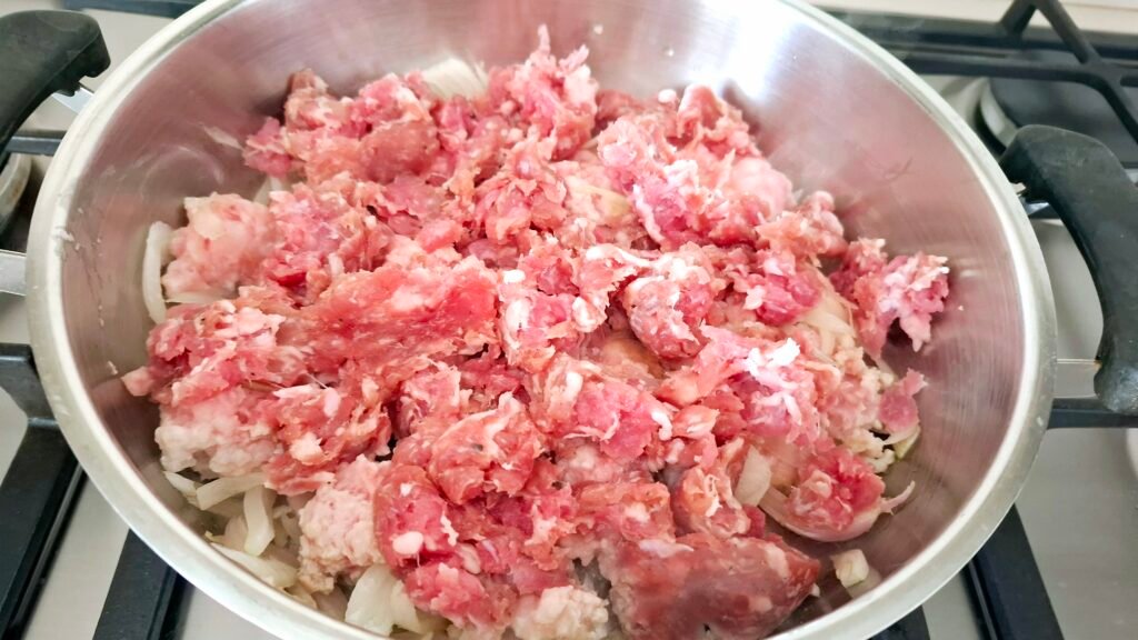 Aggiunta di salsicce sbriciolate in padella