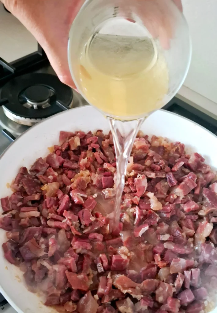Vino aggiunto a ragù di prosciutto crudo