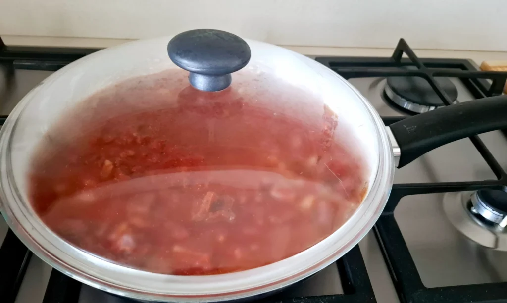 Coperchio su ragù di prosciutto crudo che sobbolle dolcemente