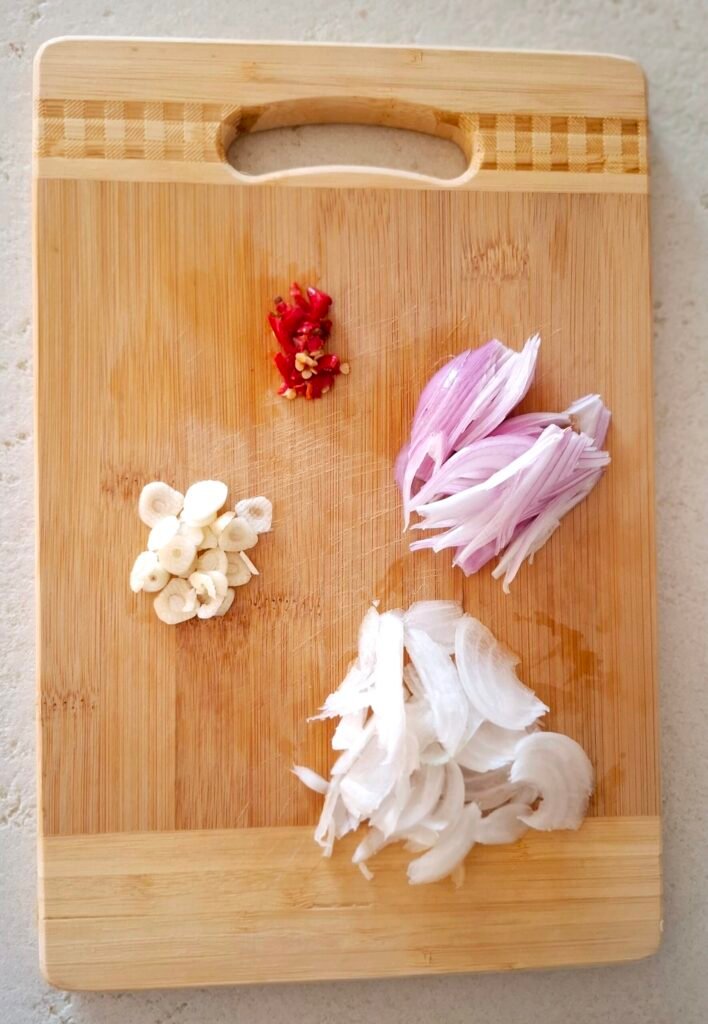 Tagliere con cipolla, scalogno, aglio e peperoncino tagliati a fettine
