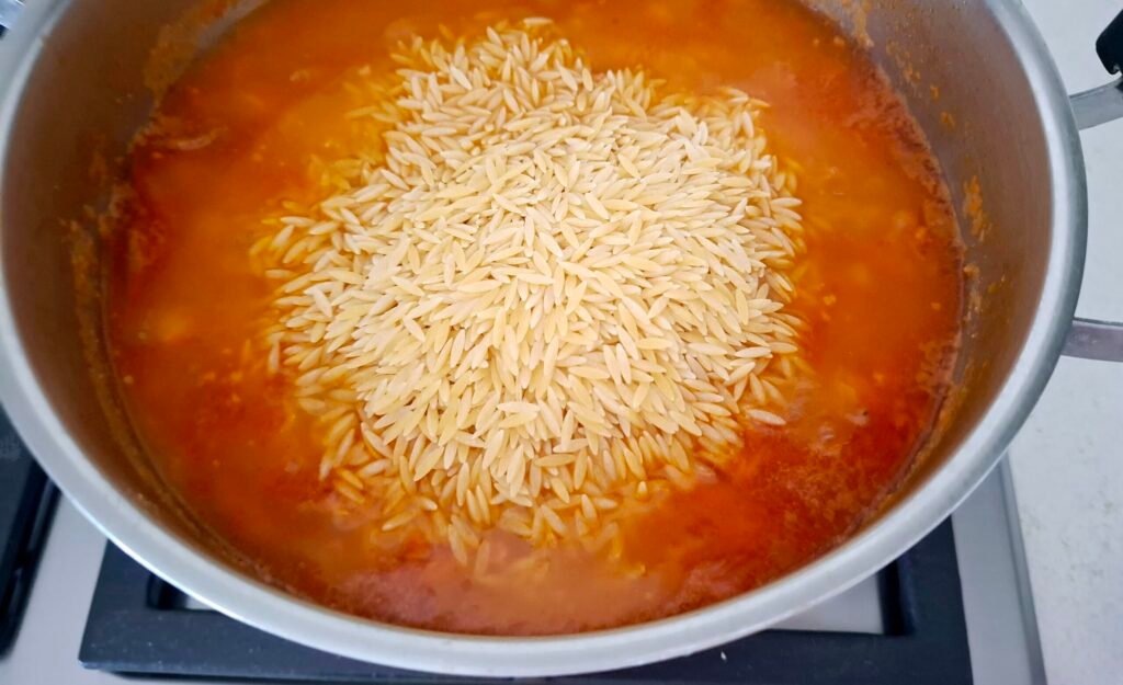 Aggiunta di pasta risone nella padella
