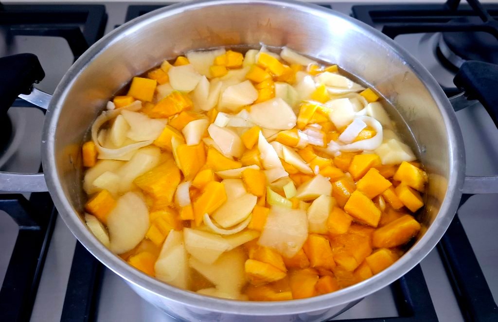 Zucca e patate a pezzetti in padella con acqua e sale che sobbollono