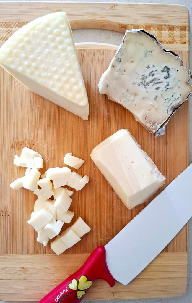 Formaggi su tagliere mentre li taglio a cubetti