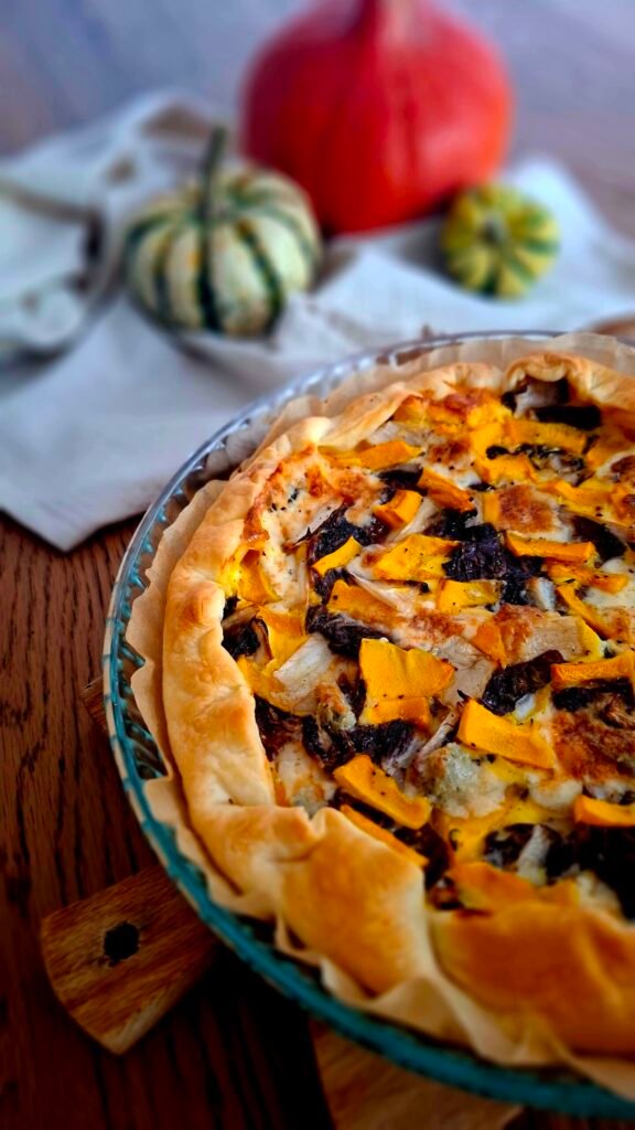 Quiche autunnale con zucca, radicchio  gorgonzola con sfondo di zucchero su tavolo in legno