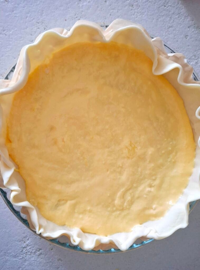 Sfoglia con composto di uovo, panna e parmigiano steso come base della quiche