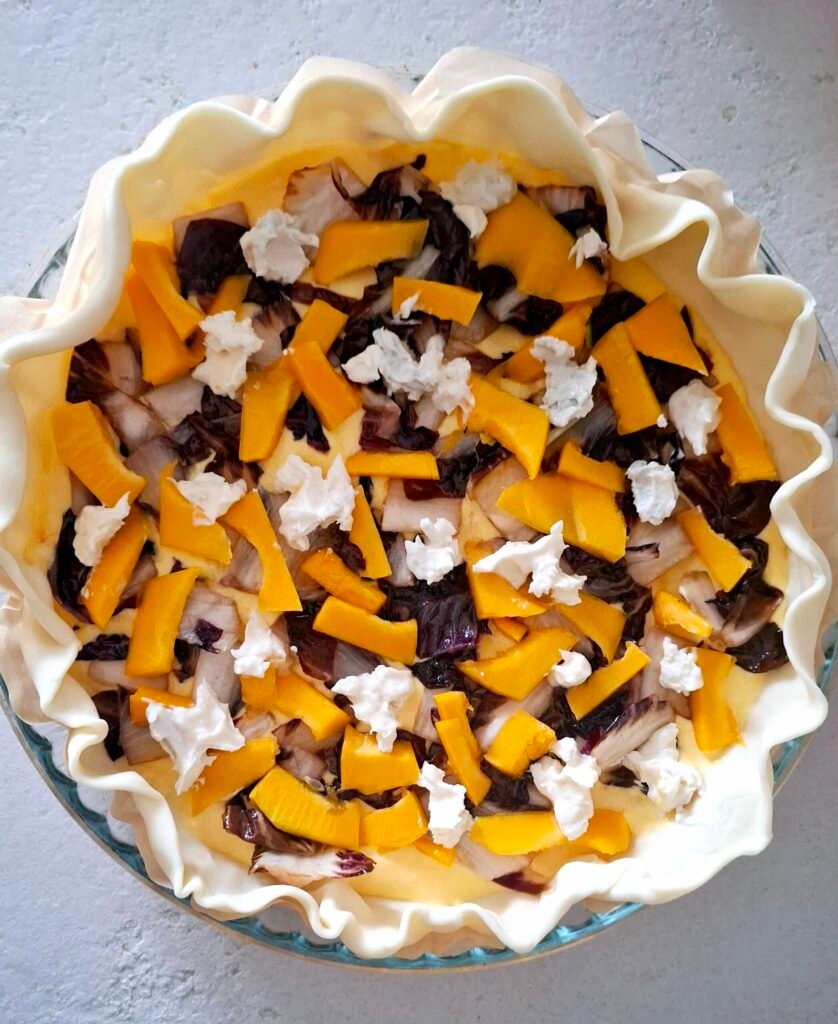 Torta salata guarnita con zucca, trevisano e gorgonzola in pirofila forno prima della cottura